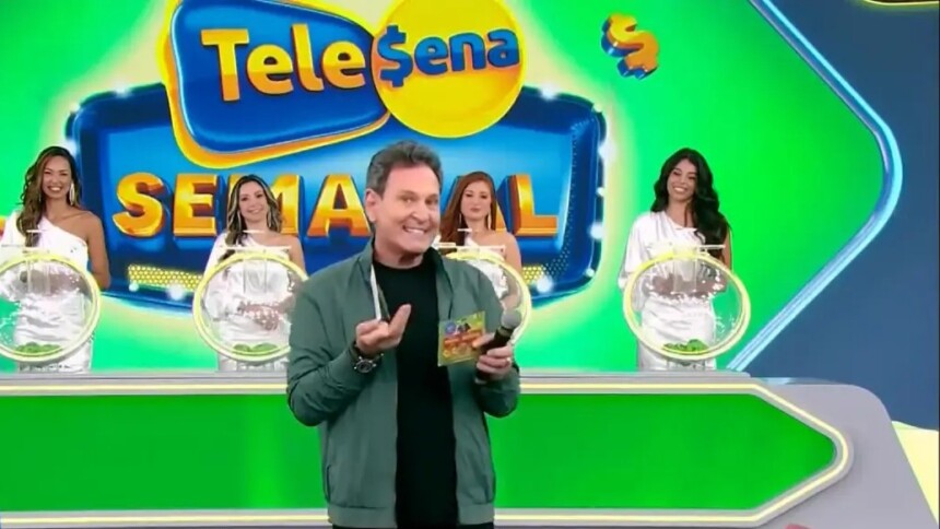Luís Ricardo segura bilhete da edição 82 da Tele Sena Semanal no cenário da atração que está verde