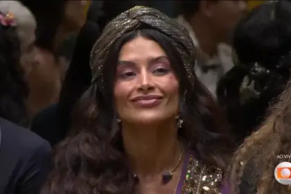 Aline Campos sentada no sofá da sala pouco antes da eliminação no BBB 26. Ela mexe a boca com semblante triste
