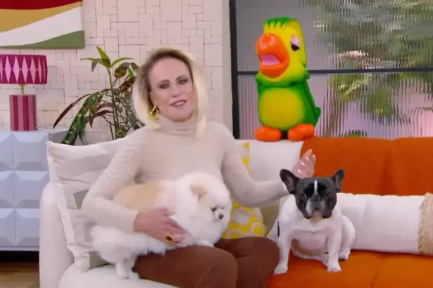 Ana Maria Braga sentada no sofá ao lado de dois cachorros e do Louro Mané na chamada do Mais Você