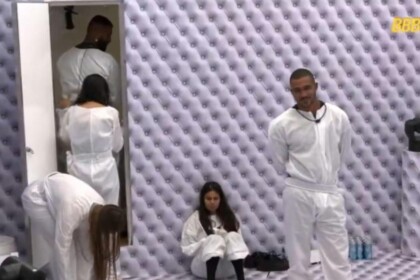 Ricardo na porta do banheiro olhando cocô na parede do quarto branco do BBB 26