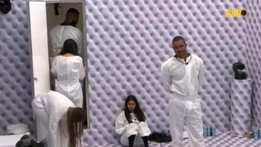 Ricardo na porta do banheiro olhando cocô na parede do quarto branco do BBB 26
