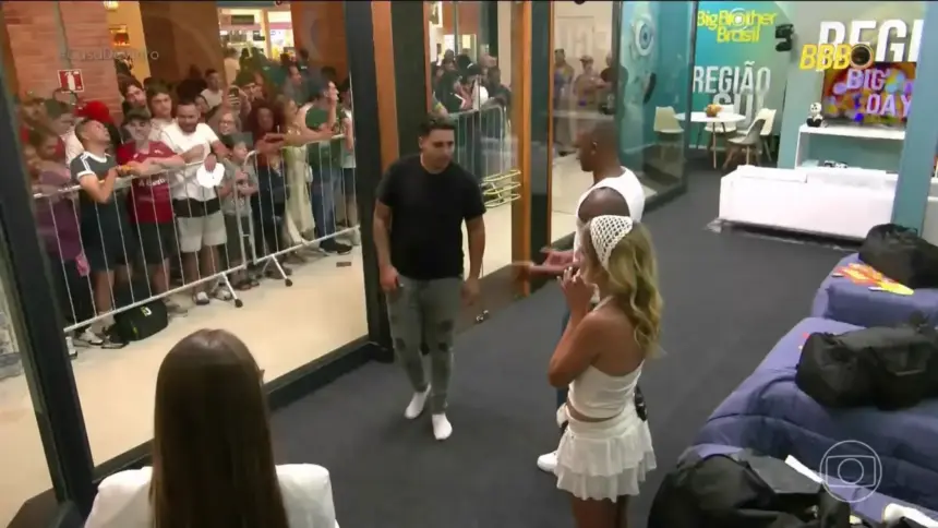 Participantes da Casa de Vidro em pé olhando para o público do lado de fora do shopping