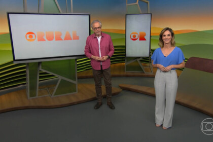 Nélson Araújo olha para Helen Martins na abertura do Globo Rural. Os dois estão próximo a duas telas com o globo do programa