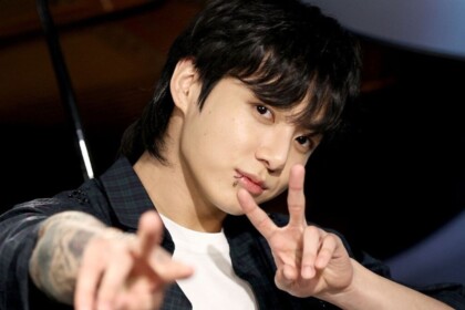 Jungkook, astro do BTS, posando fazendo sinal com os dedos
