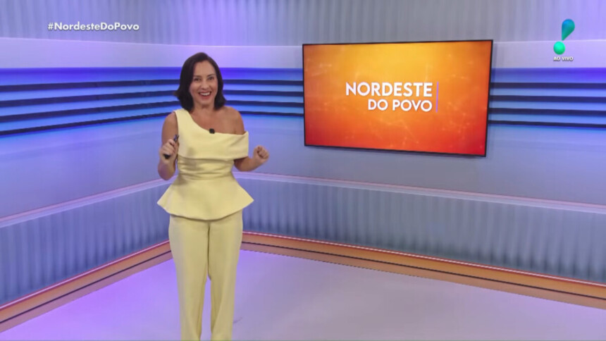 Katiuzia Rios em pé no centro do cenário do Nordeste do Povo na RedeTV!. Ela está sorridente