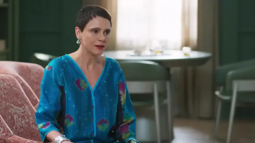 Malu Galli como Tia Celina sentada no sofá em cena da novela Vale Tudo