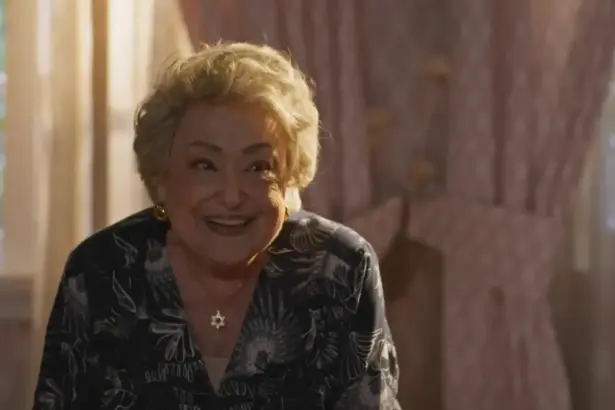 Suely Franco sorrindo em um quarto da cenografia de Dona de Mim