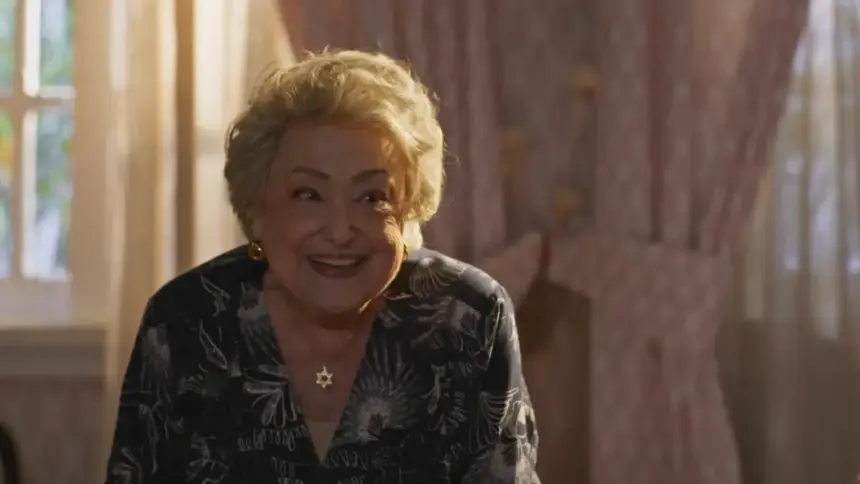 Suely Franco sorrindo em um quarto da cenografia de Dona de Mim
