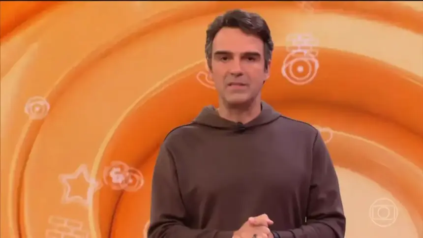 Tadeu Schmidt de casaco marrom no estúdio do BBB 26 anuncia a dinâmica da semana