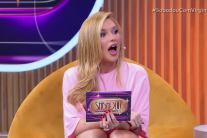 Virginia com a boca aberta, como se estivesse espantada, segurando a ficha do seu programa no SBT