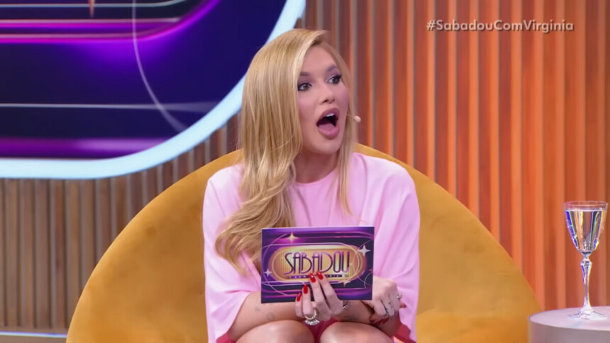 Virginia com a boca aberta, como se estivesse espantada, segurando a ficha do seu programa no SBT