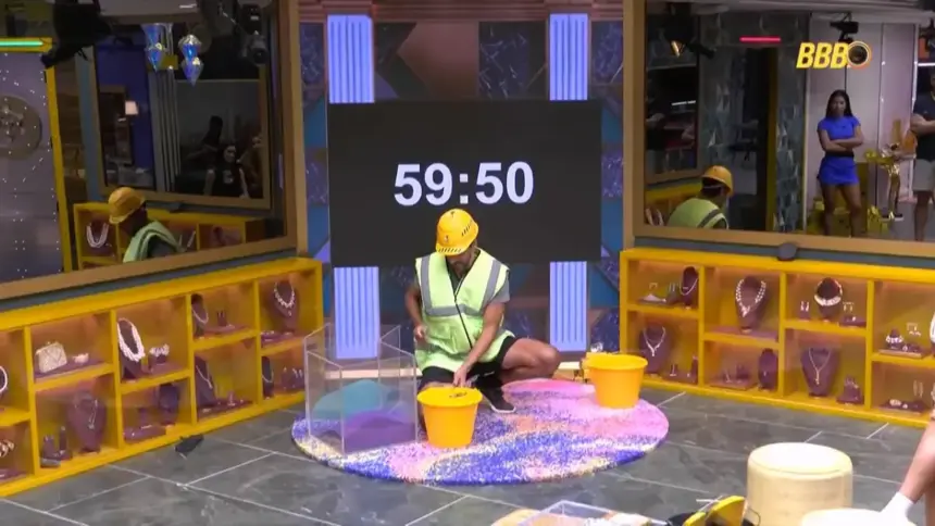 Alberto Cowboy recolhe a areia na sala de uma pote de acrílico para um balde no Castigo do Monstro do BBB 26