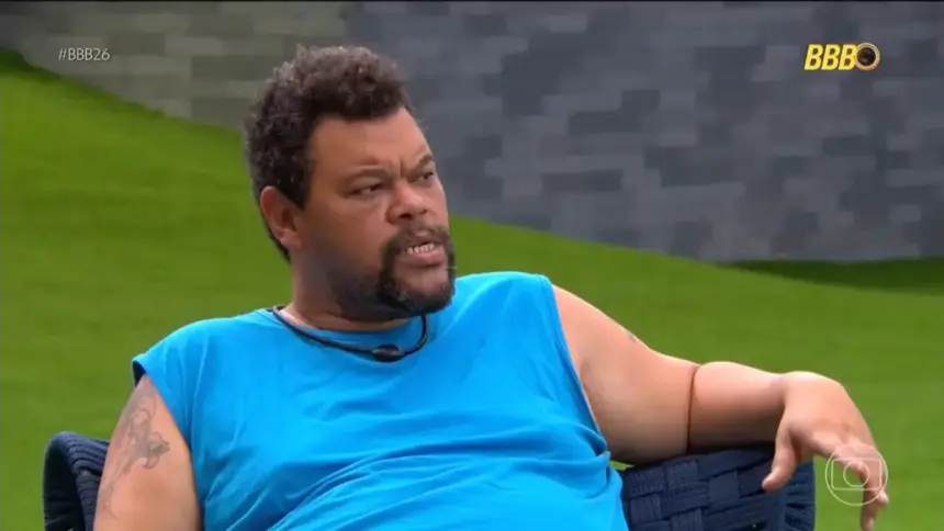 Babu veste camisa azul, sentado na área externa do BBB 26, contando para os aliados sobre o puxão de orelha da produção