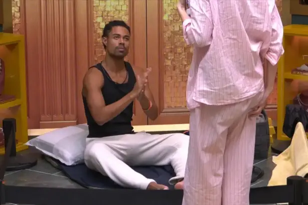 Breno esfrega as mãos passando protetor para dormir no Exilado do BBB 26. Um pequeno espaço no chão da sala