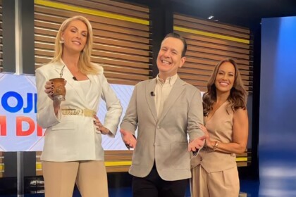Ana Hickmann segurando um chimarrão, Celso Zucatelli sorridente com os braços abertos e Renata Alves sorrindo segurando o colega de apresentação. Os três em pé lado a lado no estúdio do Hoje em Dia