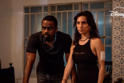 Casal de protagonistas da série Impuros com olhares atentos dentro de uma casa simples no Rio de Janeiro