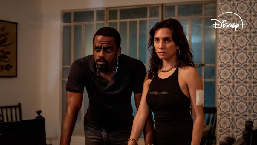 Casal de protagonistas da série Impuros com olhares atentos dentro de uma casa simples no Rio de Janeiro