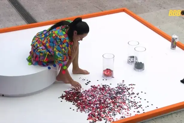 Jordana cata confetes no chão da área externa do BBB 26 durante Castigo do Monstro