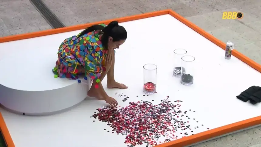 Jordana cata confetes no chão da área externa do BBB 26 durante Castigo do Monstro