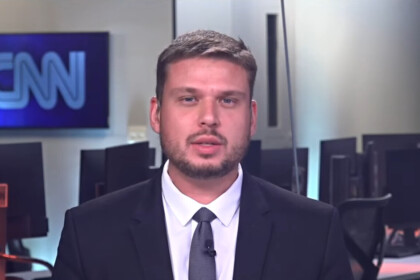 Pedro Teixeira de terno e gravata na redação da CNN Brasil