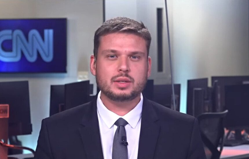 Pedro Teixeira de terno e gravata na redação da CNN Brasil