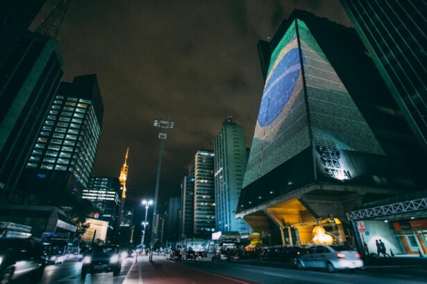 cars traveling on road between buildings during nighttime