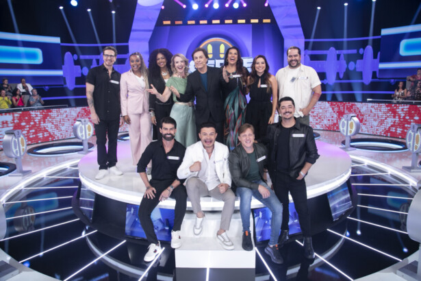 Tom Cavalcante ao lado dos famosos convidados do Acerte ou Caia! no centro do palco. Todos estão sorridentes