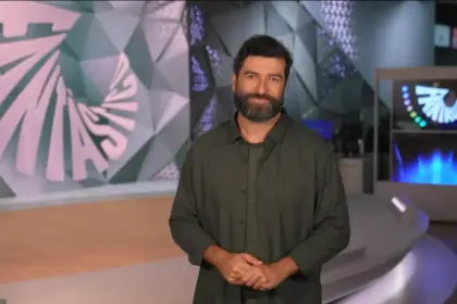 Rodrigo Carvalho sorridente no palco do Fantástico gravando a chamada do programa