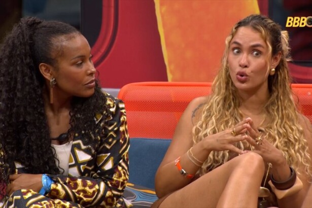 Sol Vega ao lado de Sarah Andrade que faz bico com a boca conversando sobre Ana Paula no BBB 26. Eles estão sentados no sofá da área externa