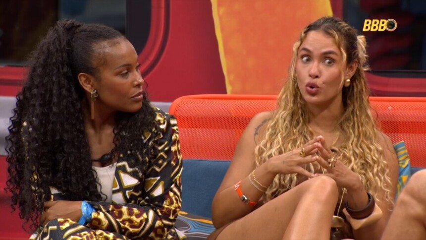 Sol Vega ao lado de Sarah Andrade que faz bico com a boca conversando sobre Ana Paula no BBB 26. Eles estão sentados no sofá da área externa
