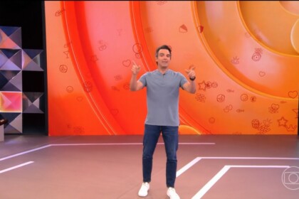 Tadeu Schmidt de camisa cinza e calça jeans apresentando a dinâmica do BBB 26