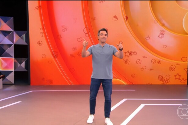 Tadeu Schmidt de camisa cinza e calça jeans apresentando a dinâmica do BBB 26