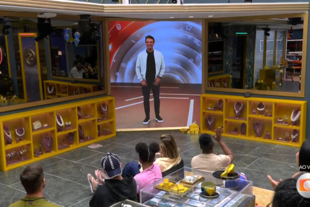 Tadeu Schmidt anunciando o fim do Tá com Nada em conversa com os brothers através do telão na sala