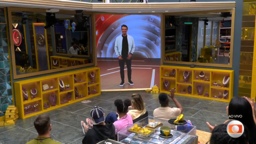 Tadeu Schmidt anunciando o fim do Tá com Nada em conversa com os brothers através do telão na sala