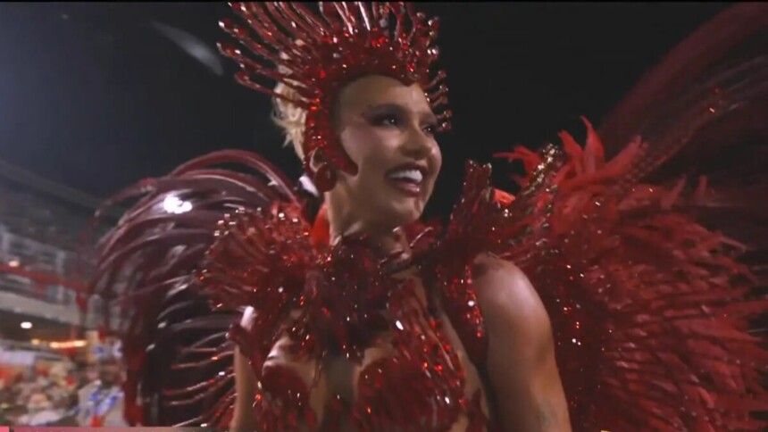 Virginia Fonseca com fantasia vermelha desfilando na Sapucaí e sorrindo para o público