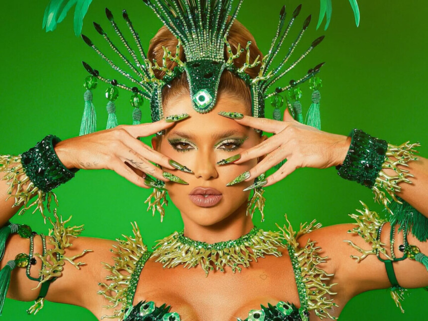 Virginia de roupa verde com as unhas de gel também verde e assessórios do carnaval 2026