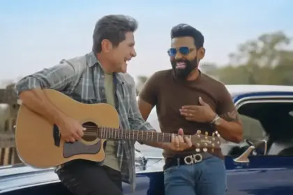 Daniel segura um violão e sorrir ao lado de Pablo que está em pé no carro