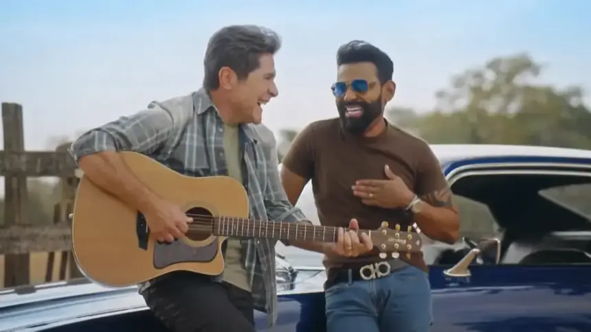 Daniel segura um violão e sorrir ao lado de Pablo que está em pé no carro