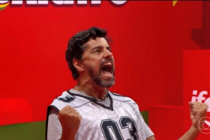 Alberto Cowboy com a boca aberta gritando e levantando os braços jogado ao chão da Prova do Líder do BBB 26
