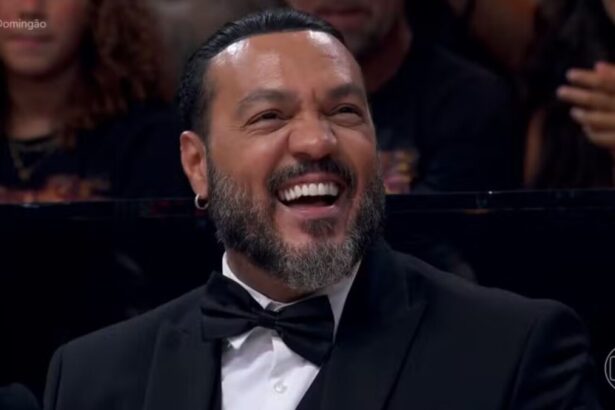 Belo, de terno e gravata borboleta, sorrindo, em trecho do Domingão