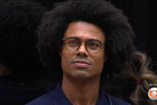 Breno usa óculos e olha para o telão do BBB 26