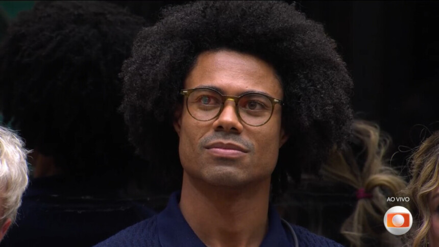Breno usa óculos e olha para o telão do BBB 26