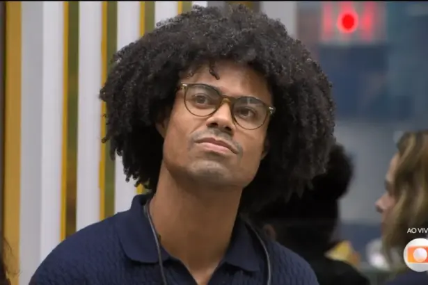 Breno com semblante triste olhando para a telão da sala do BBB 26 antes de Tadeu anunciar a eliminação