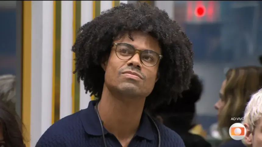 Breno com semblante triste olhando para a telão da sala do BBB 26 antes de Tadeu anunciar a eliminação