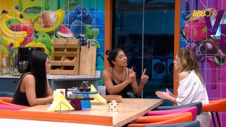 Marciele sentada na cozinha VIP do BBB 26 em frente a Ana Paula Renault gesticulando durante a briga
