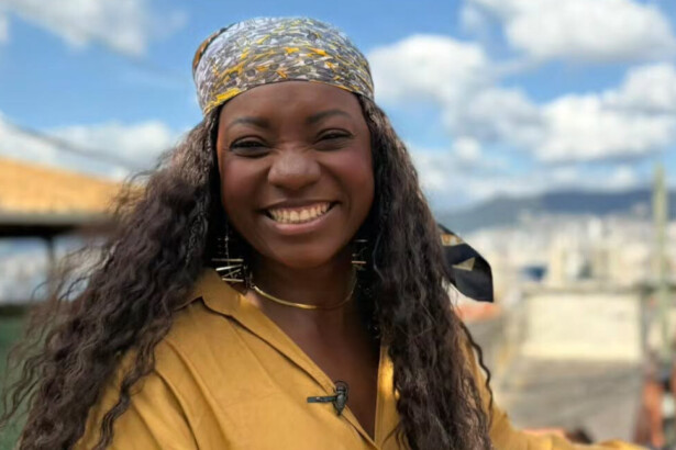 Adriana Araújo sorridente e em pé em um morro