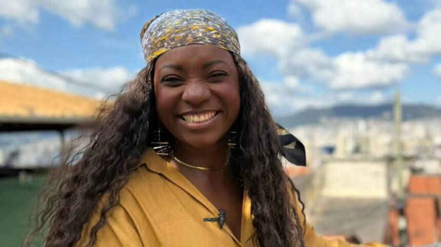 Adriana Araújo sorridente e em pé em um morro