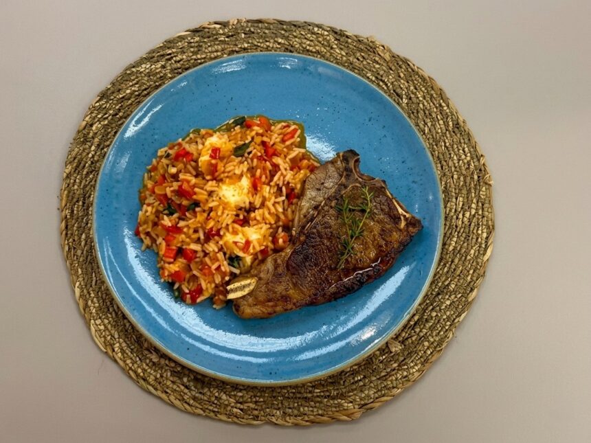 Chuleta na frigideira com arroz de tomate em um prato azul em cima da mesa do É de Casa