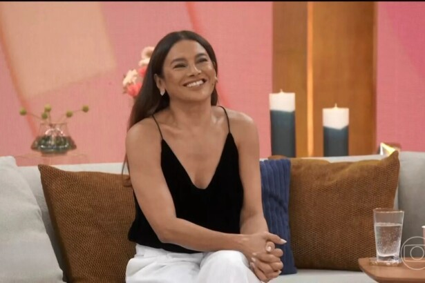 Dira Paes sorridente sentada no sofá do programa Encontro
