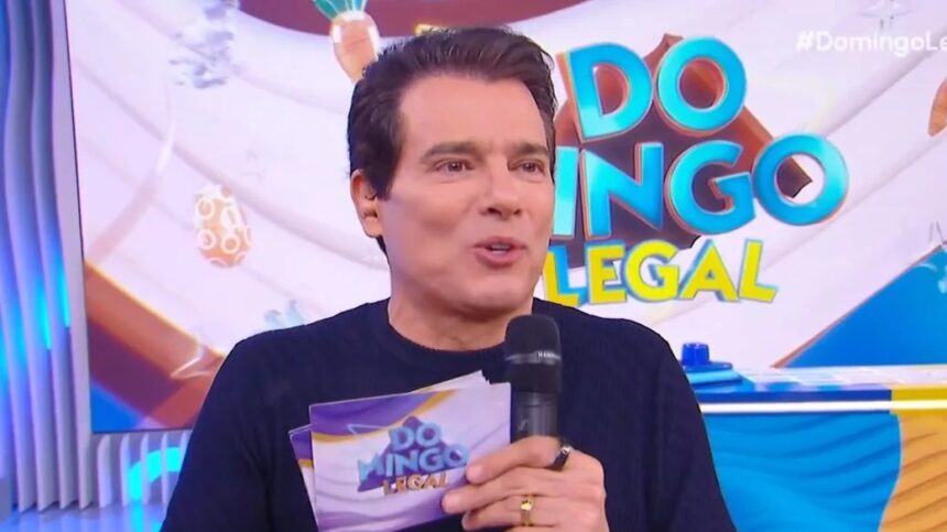 Celso Portiolli sorridente provando ovos de Páscoa no cenário do Domingo Legal